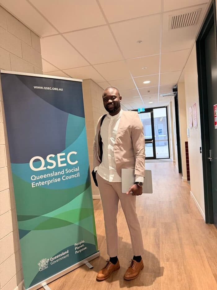 Noah Oloja beside the Queensland Social Enterprise Council banner
