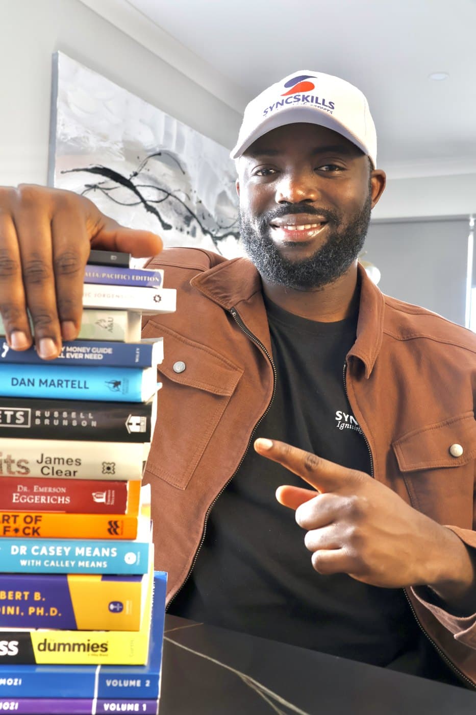 Noah with his stack of business books, including Dan Martell, Russell Brunson and Alex Hormozi